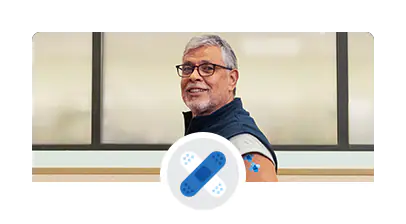 Man with his shirt sleeve pulled up, showing a blue band-aid on his shoulder.